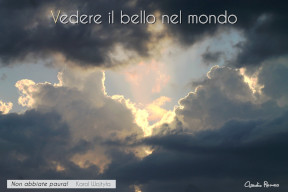 Un raggio di sole al centro di nuvole nere. Il testo dice: "Vedere il bello nel mondo" e riporta una frase di Giovanni Paolo II: "Non abbiate paura!"