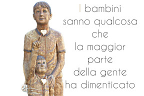 Statua in legno di un bambino che indica una stella. Opera di Sirio Vierin. Il testo riporta una frase di Keith Haring: "I bambini sanno qualcosa che la maggior parte della gente ha dimenticato"