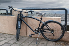 Bicicletta nera appoggiata alla ringhiera del lungomare