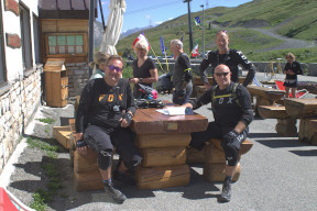 Un gruppo di motociclisti che si ristorano a un tavolo di un bar in montagna