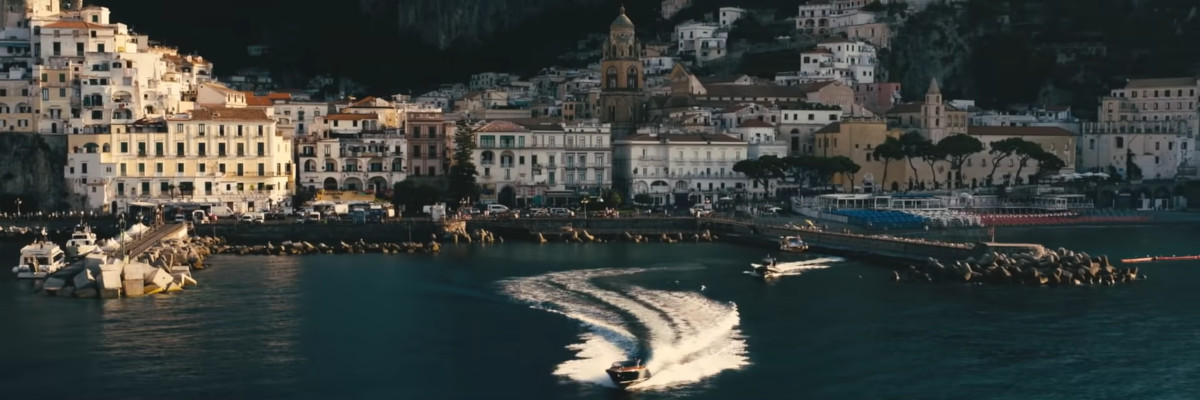 Piccolo porto con un motoscafo che si allontana velocemente