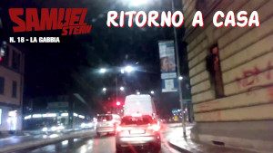 Una strada di Milano di notte, con le auto ferme al semaforo