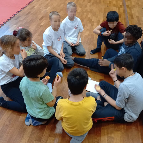 Una decina di bambini seduti in cerchio in una palestra